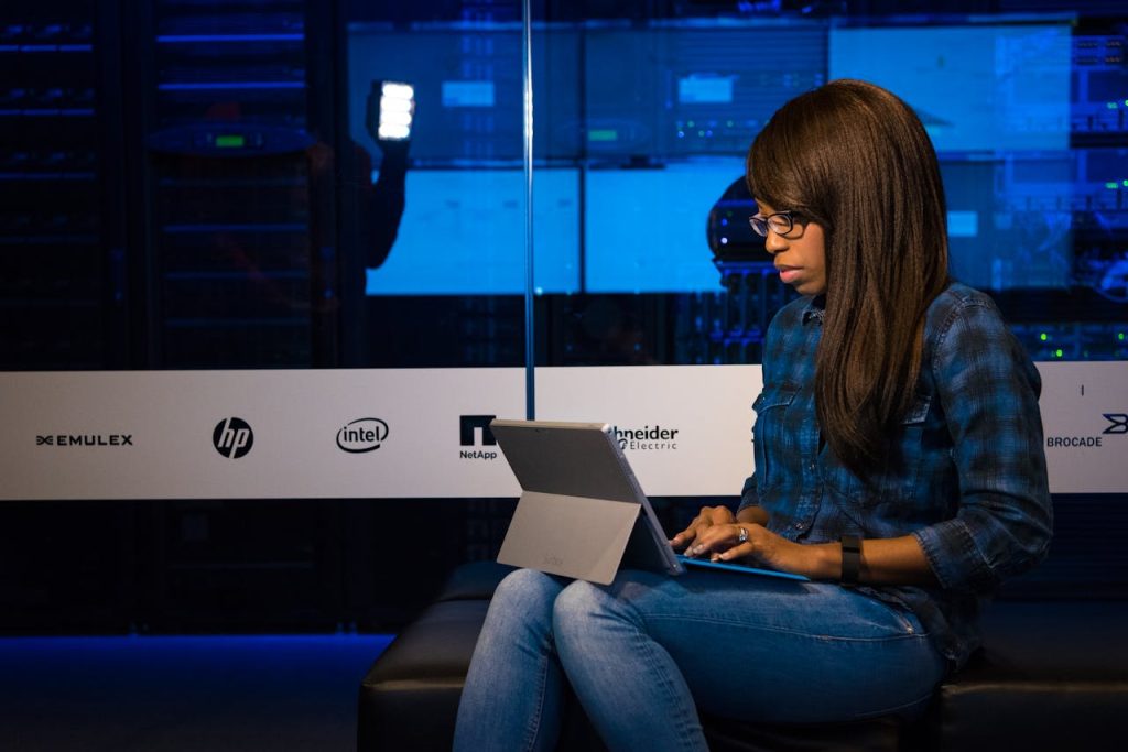 Professional woman working on laptop in a server room, showcasing technology and remote work.